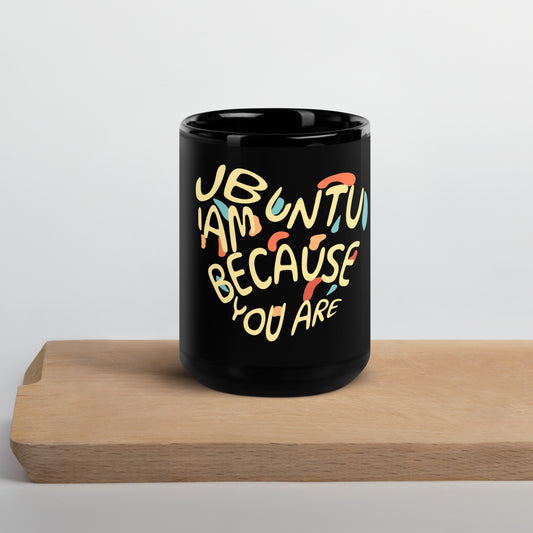 Black mug with colorful "Ubuntu I am because you are" design on a wooden block against a light gray background. front view